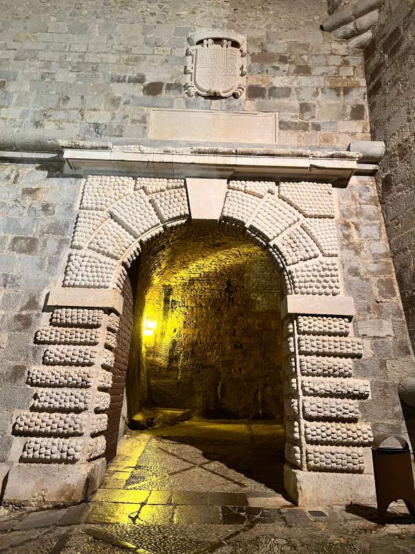 Puerta histórica del Portal Fosc en Peñíscola con iluminación amarilla.